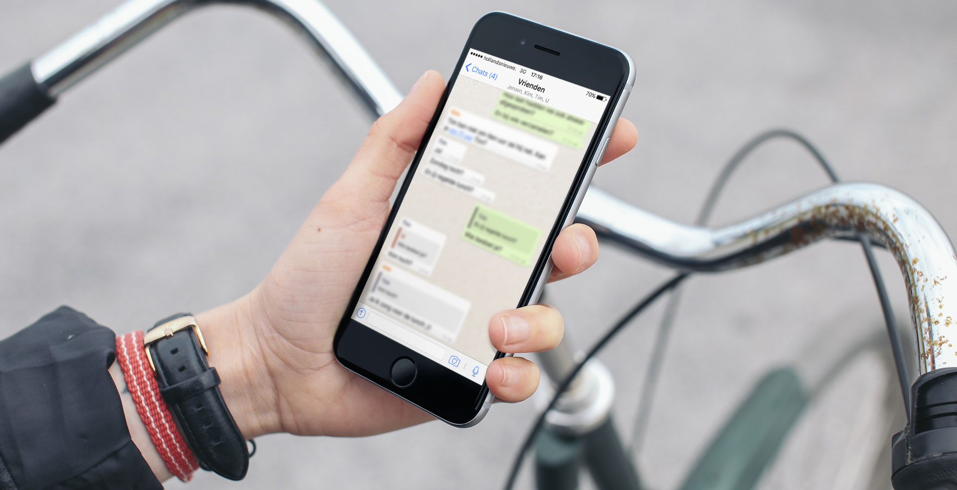 Smartphone in de hand met fietsstuur op achtergrond