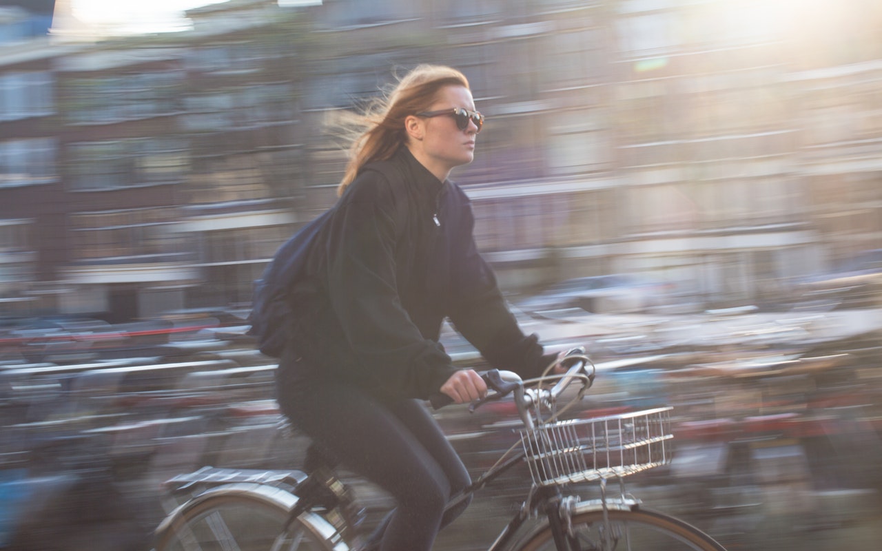 Jonge vrouw met zonnebril op fiets in stad